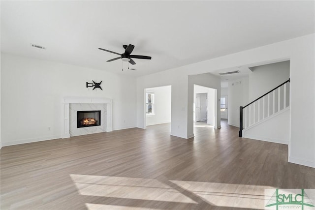 unfurnished living room with ceiling fan, a fireplace, and light hardwood / wood-style floors