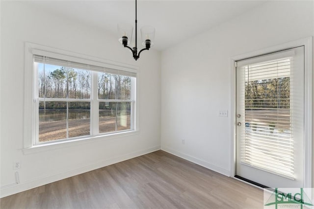 unfurnished dining area with a chandelier and light wood-type flooring