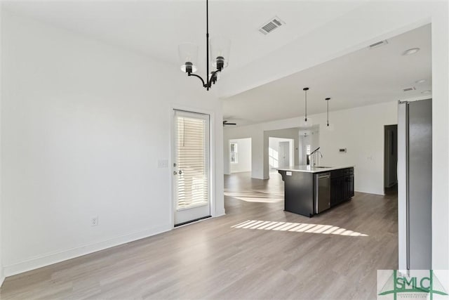 kitchen featuring sink, dishwasher, a kitchen island with sink, hanging light fixtures, and light hardwood / wood-style floors