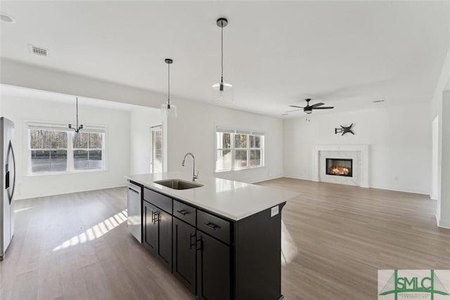 kitchen featuring a fireplace, decorative light fixtures, sink, a kitchen island with sink, and stainless steel appliances