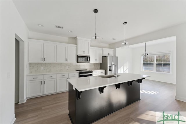 kitchen with a breakfast bar, pendant lighting, sink, white cabinets, and stainless steel appliances