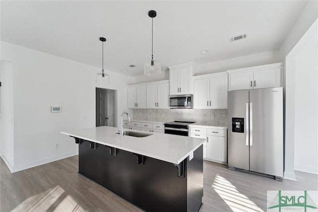 kitchen with appliances with stainless steel finishes, sink, a center island with sink, and white cabinets