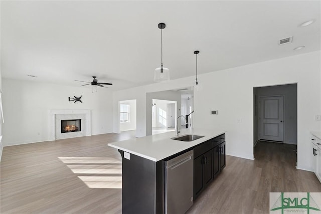 kitchen with sink, hanging light fixtures, dishwasher, an island with sink, and light hardwood / wood-style floors