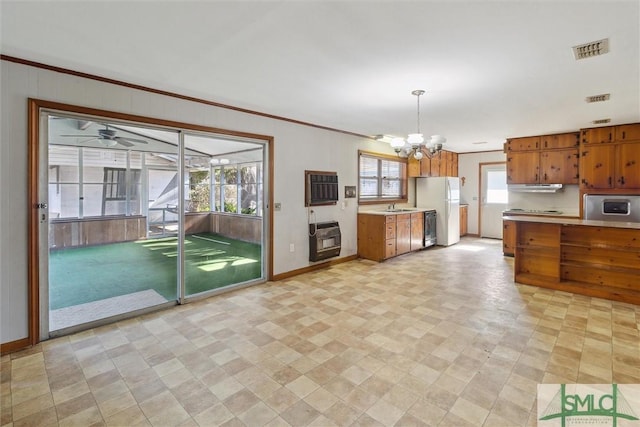 kitchen featuring heating unit, decorative light fixtures, sink, white fridge, and crown molding