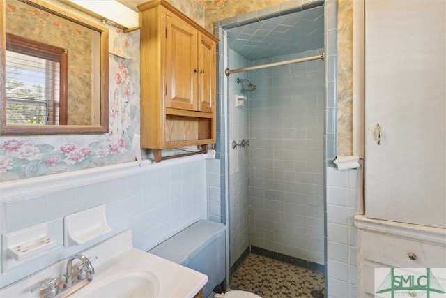 bathroom with vanity, tiled shower, tile walls, and toilet