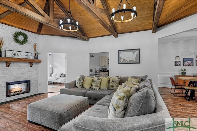 living room featuring dark hardwood / wood-style floors, a notable chandelier, a fireplace, wooden ceiling, and beamed ceiling