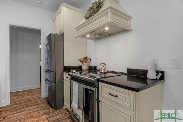 kitchen featuring stainless steel appliances, wood-type flooring, custom exhaust hood, and cream cabinetry