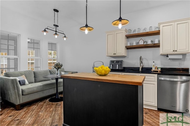 kitchen with sink, butcher block counters, hanging light fixtures, wood-type flooring, and stainless steel dishwasher