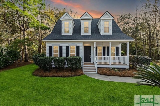 new england style home featuring a porch and a lawn