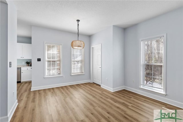 unfurnished dining area with a textured ceiling and light hardwood / wood-style floors