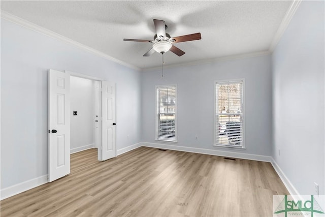 empty room featuring crown molding, a textured ceiling, and light wood-type flooring