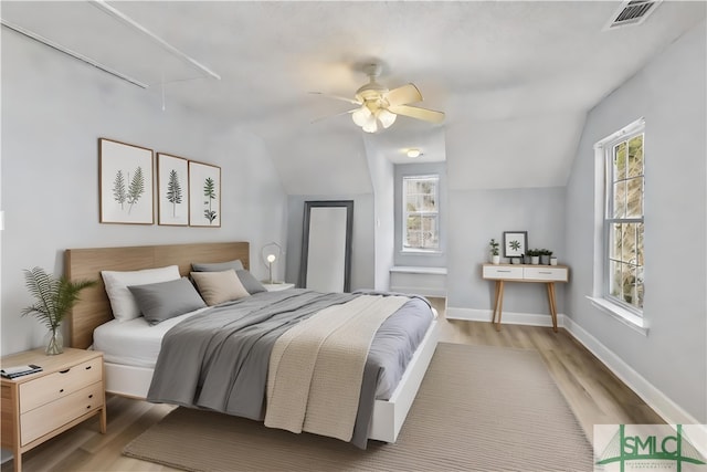 bedroom featuring multiple windows, wood-type flooring, and vaulted ceiling