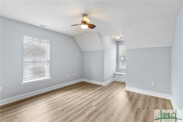 bonus room featuring vaulted ceiling, ceiling fan, light hardwood / wood-style floors, and a textured ceiling