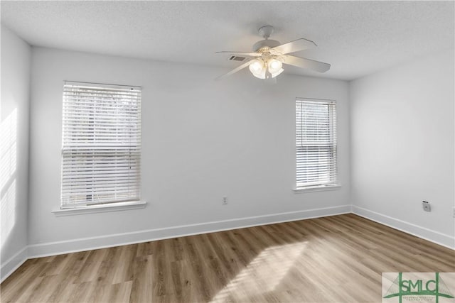 empty room featuring ceiling fan, light hardwood / wood-style flooring, and a textured ceiling