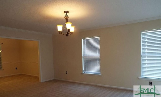 spare room with crown molding and a notable chandelier