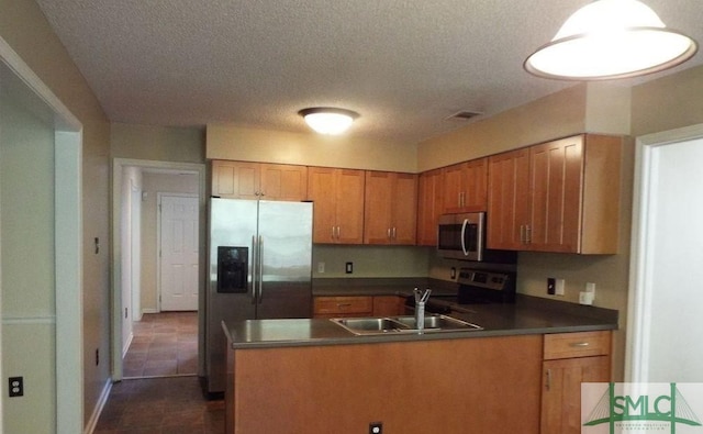 kitchen with appliances with stainless steel finishes, sink, dark tile patterned flooring, kitchen peninsula, and a textured ceiling