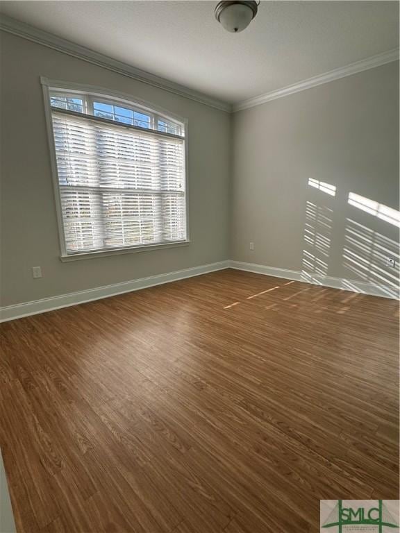 unfurnished room with dark wood-style floors, ornamental molding, and baseboards