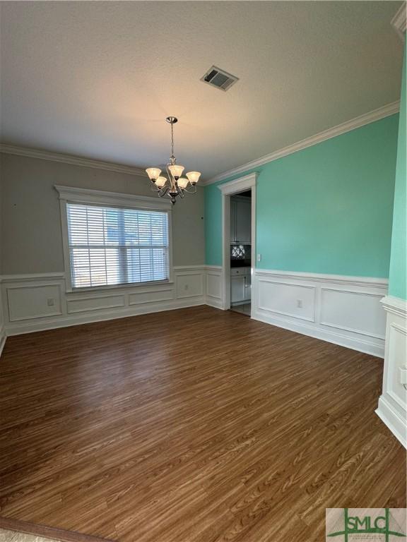 709 Eden Ln, Hinesville, GA 31313 - unfurnished dining area with an inviting chandelier, crown molding, visible vents, and dark wood-type flooring