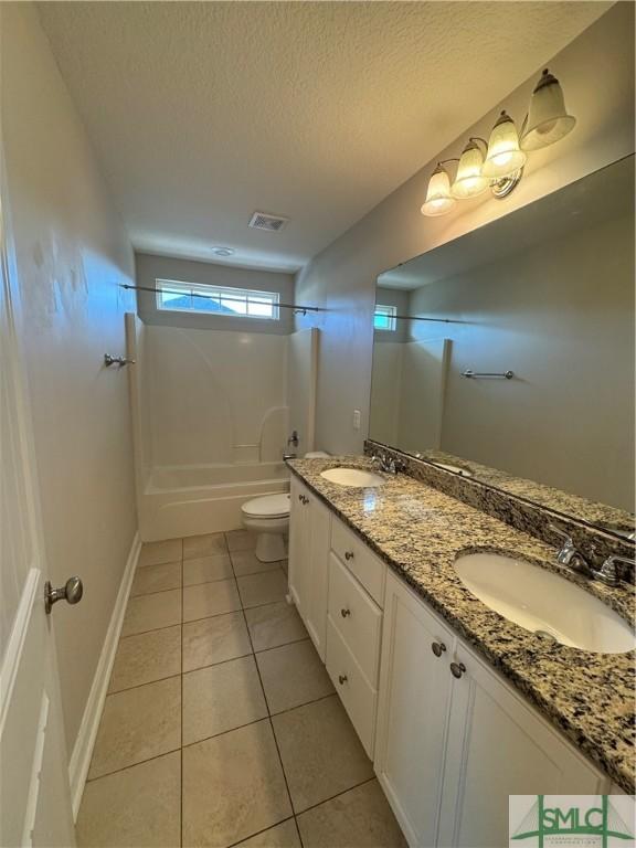 709 Eden Ln, Hinesville, GA 31313 - bathroom with toilet, a textured ceiling, a sink, and tile patterned floors