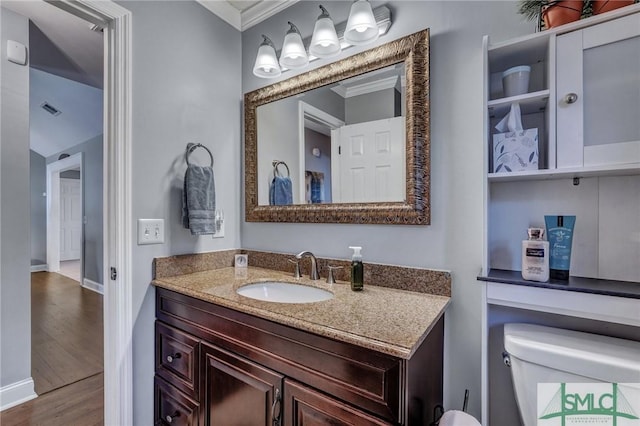 bathroom featuring hardwood / wood-style flooring, ornamental molding, vanity, and toilet