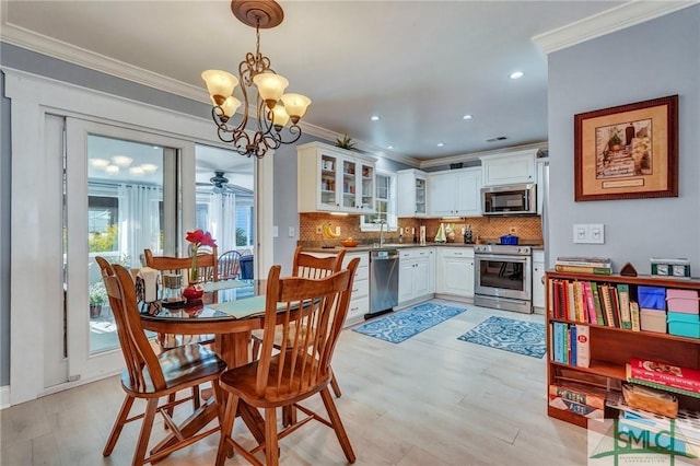 dining area featuring crown molding, ceiling fan with notable chandelier, and light hardwood / wood-style flooring