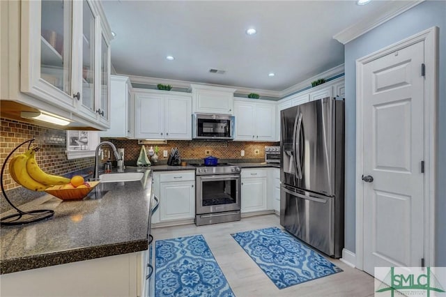 kitchen featuring sink, appliances with stainless steel finishes, white cabinetry, backsplash, and ornamental molding