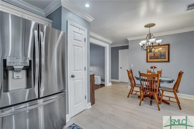 dining space featuring an inviting chandelier, crown molding, and light hardwood / wood-style floors