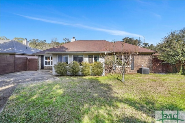 back of property with central AC unit and a lawn