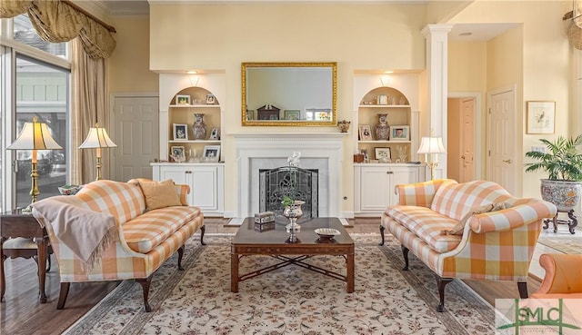 living room with decorative columns, wood-type flooring, and built in features