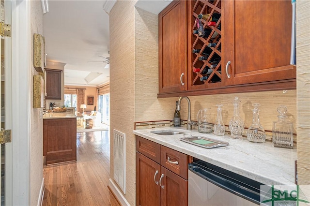 kitchen featuring sink, light hardwood / wood-style flooring, dishwasher, ceiling fan, and light stone countertops