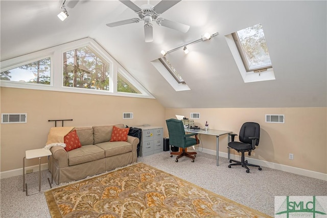 carpeted office with track lighting and vaulted ceiling with skylight