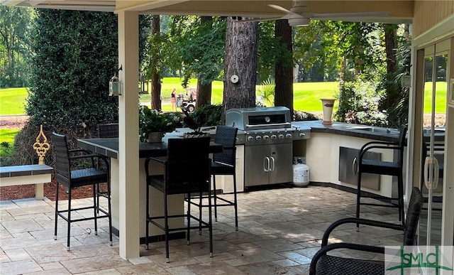 view of patio / terrace with a bar, area for grilling, and ceiling fan