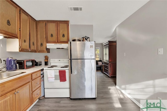 kitchen featuring wood-type flooring, sink, stainless steel fridge, and white range with electric cooktop