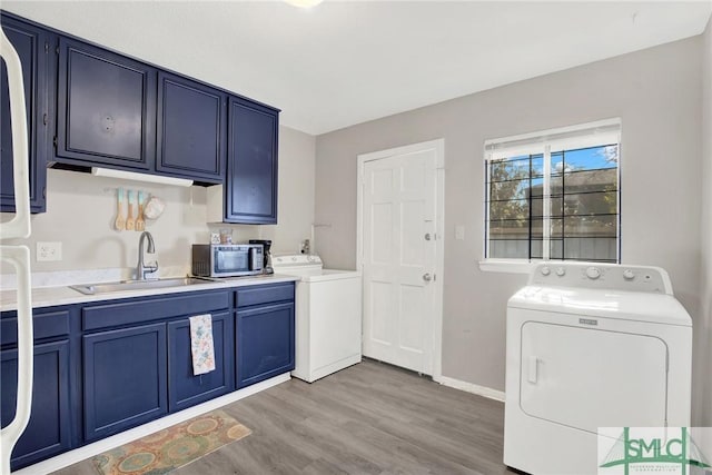 laundry area featuring cabinets, separate washer and dryer, sink, and light wood-type flooring