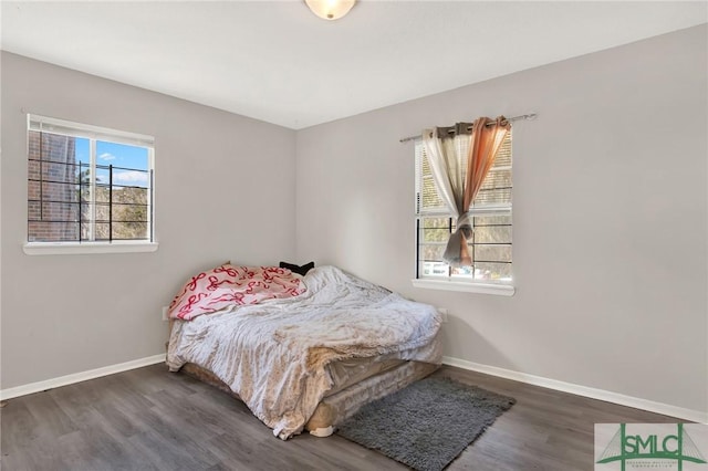 bedroom with dark wood-type flooring and multiple windows