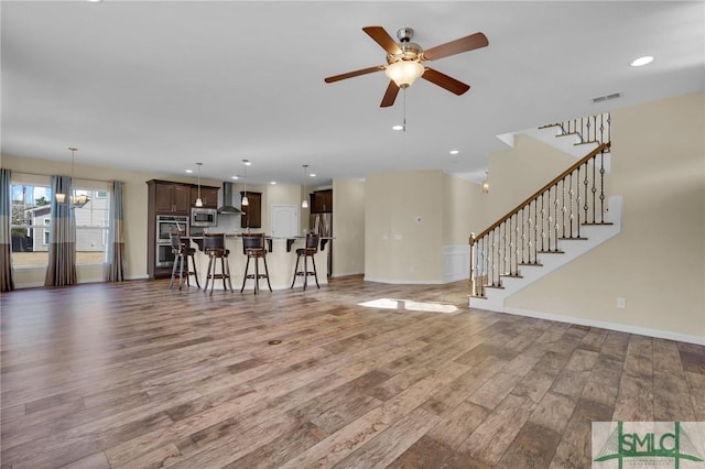 unfurnished living room featuring hardwood / wood-style flooring and ceiling fan with notable chandelier