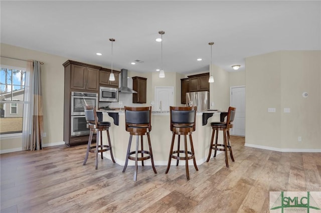 kitchen with pendant lighting, a center island, wall chimney exhaust hood, and appliances with stainless steel finishes