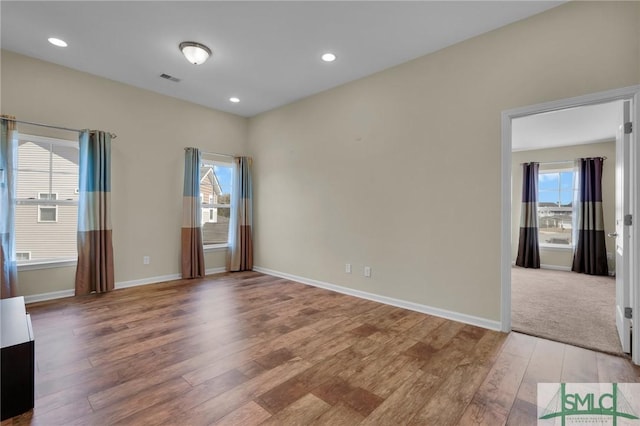 empty room with a healthy amount of sunlight and hardwood / wood-style floors