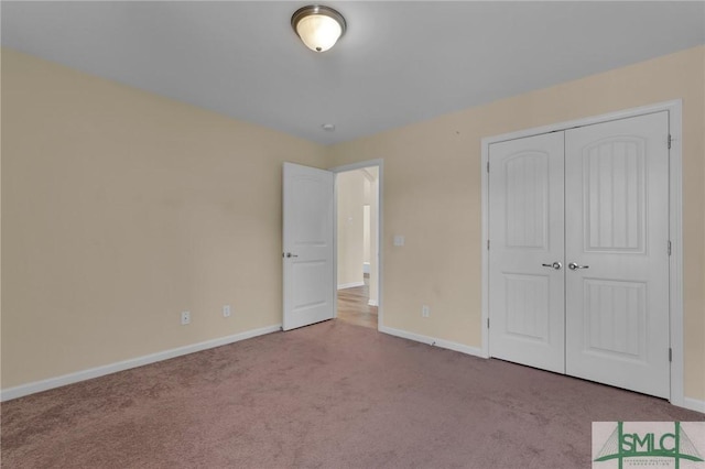 unfurnished bedroom featuring light carpet and a closet