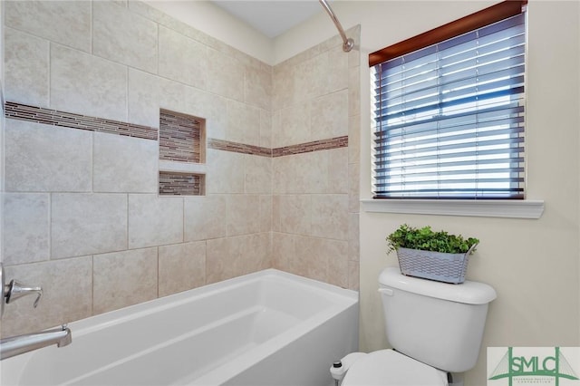 bathroom featuring tiled shower / bath combo and toilet