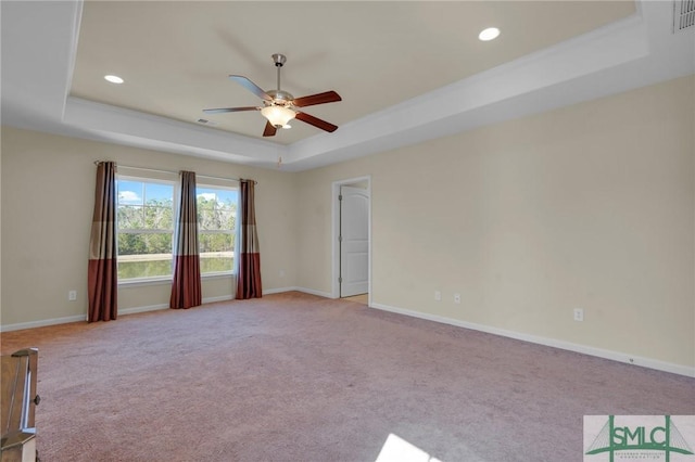 carpeted empty room with ceiling fan and a tray ceiling