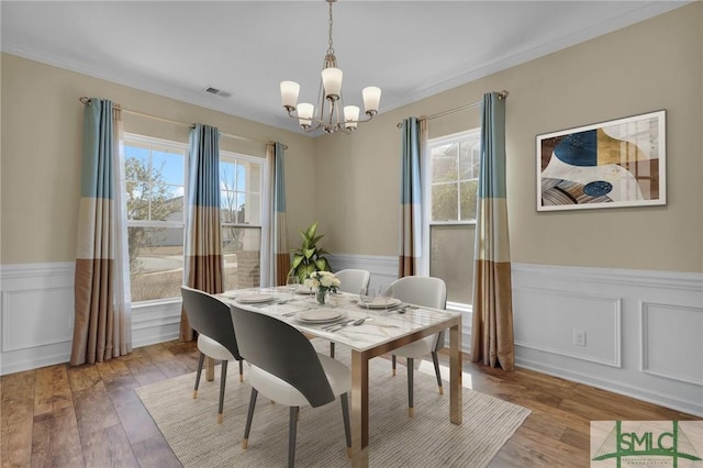 dining room with crown molding, hardwood / wood-style flooring, and a chandelier