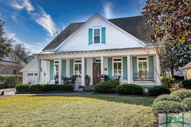 view of front of home featuring a garage, a front yard, and a porch