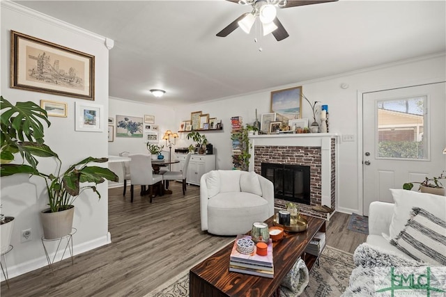 living room featuring a fireplace, dark wood-type flooring, ornamental molding, and ceiling fan