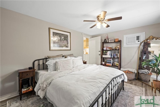 bedroom with hardwood / wood-style floors, a wall mounted AC, and ceiling fan