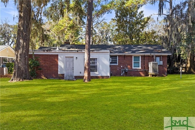 rear view of house with central air condition unit and a lawn