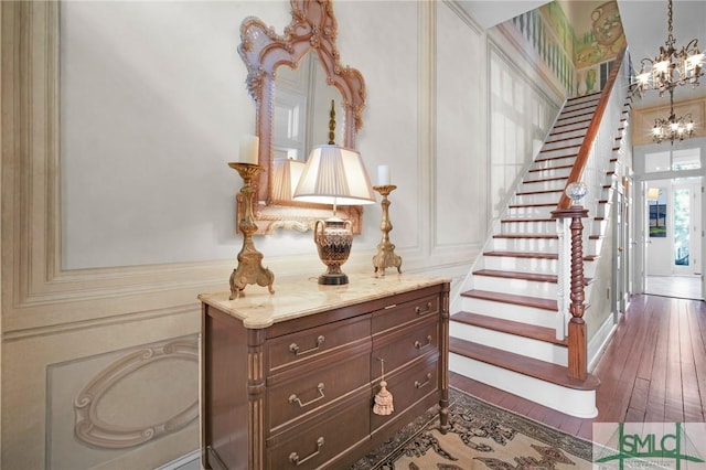 stairway with a notable chandelier and hardwood / wood-style floors