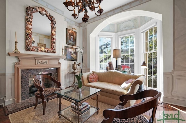 living area featuring crown molding, a chandelier, a fireplace, and light hardwood / wood-style flooring