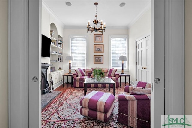 living room with hardwood / wood-style flooring, crown molding, built in features, and an inviting chandelier