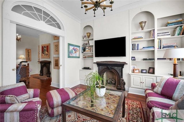 living room with ornamental molding, dark hardwood / wood-style flooring, built in features, and a notable chandelier